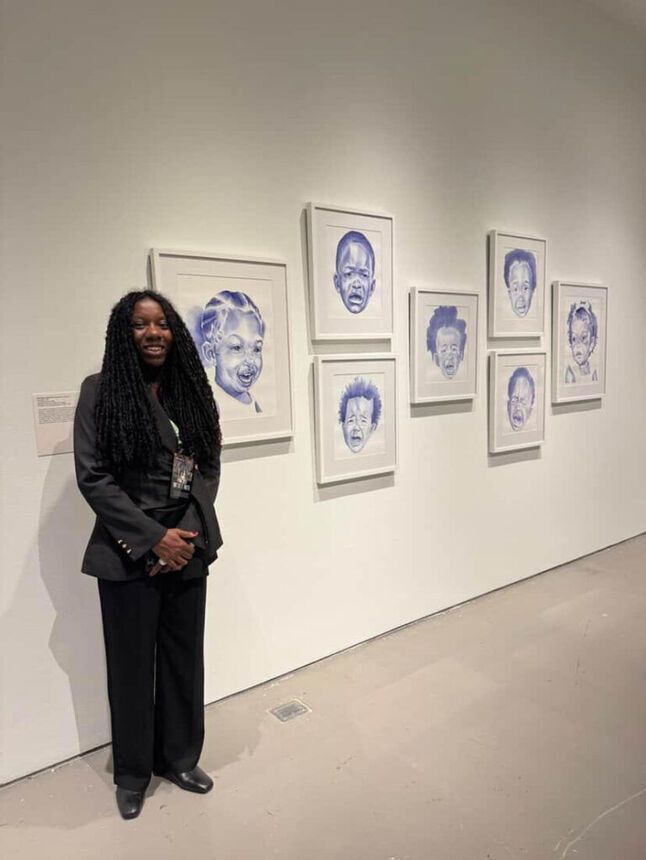 Kyra standing next to her artwork in a gallery